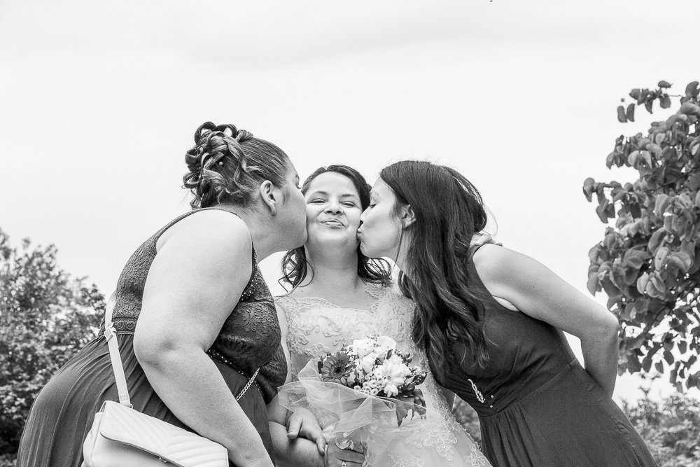 La soeur et la meilleure amie embrassent la mariée en N&B photo by kalone